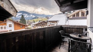 Un balcon avec vue sur les montagnes, des balustrades en bois et une table avec des chaises.