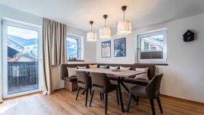 Un espace de salle à manger moderne avec une table en bois, des chaises à revêtement gris et des luminaires suspendus.