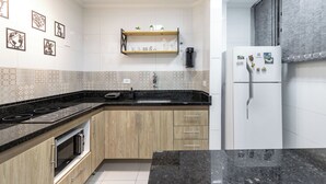 A modern kitchen with wooden cabinets, a black countertop, a built-in oven, and a white refrigerator. - Premium RJ - Consulado (Rio de Janeiro)