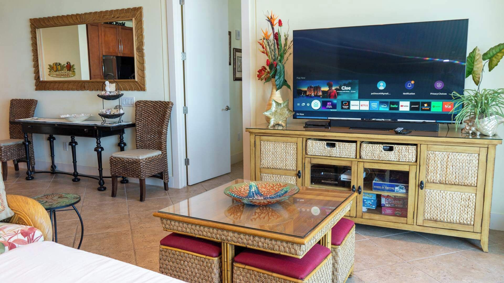 A living room with a television, wicker furniture, a dining table, and a cabinet with storage boxes.