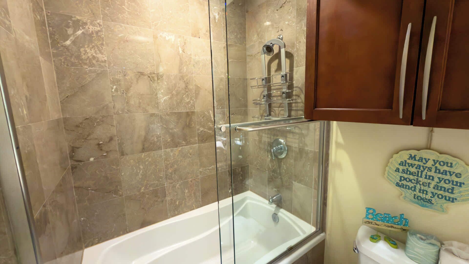 A bathroom with a glass-enclosed shower, a white bathtub, and a toilet.