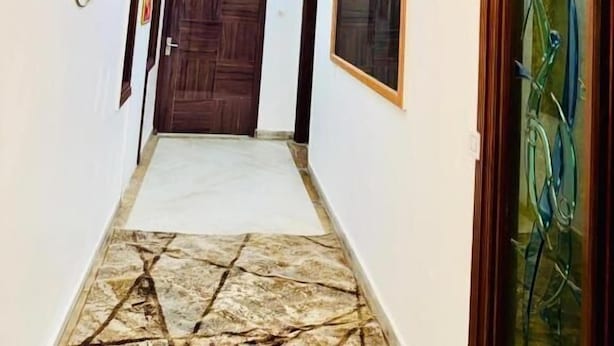 Um corredor com piso estampado, luminária no teto e obras de arte emolduradas nas paredes.