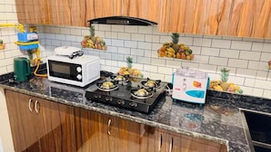 Uma cozinha com fogão a gás, micro-ondas e liquidificador na bancada.