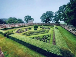 A formal garden with geometric patterns and a central fountain.