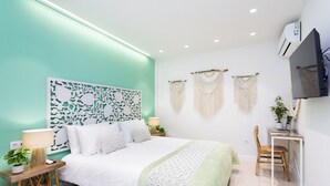 Una camera da letto con un letto, comodini, una scrivania e decorazioni macramè alle pareti.