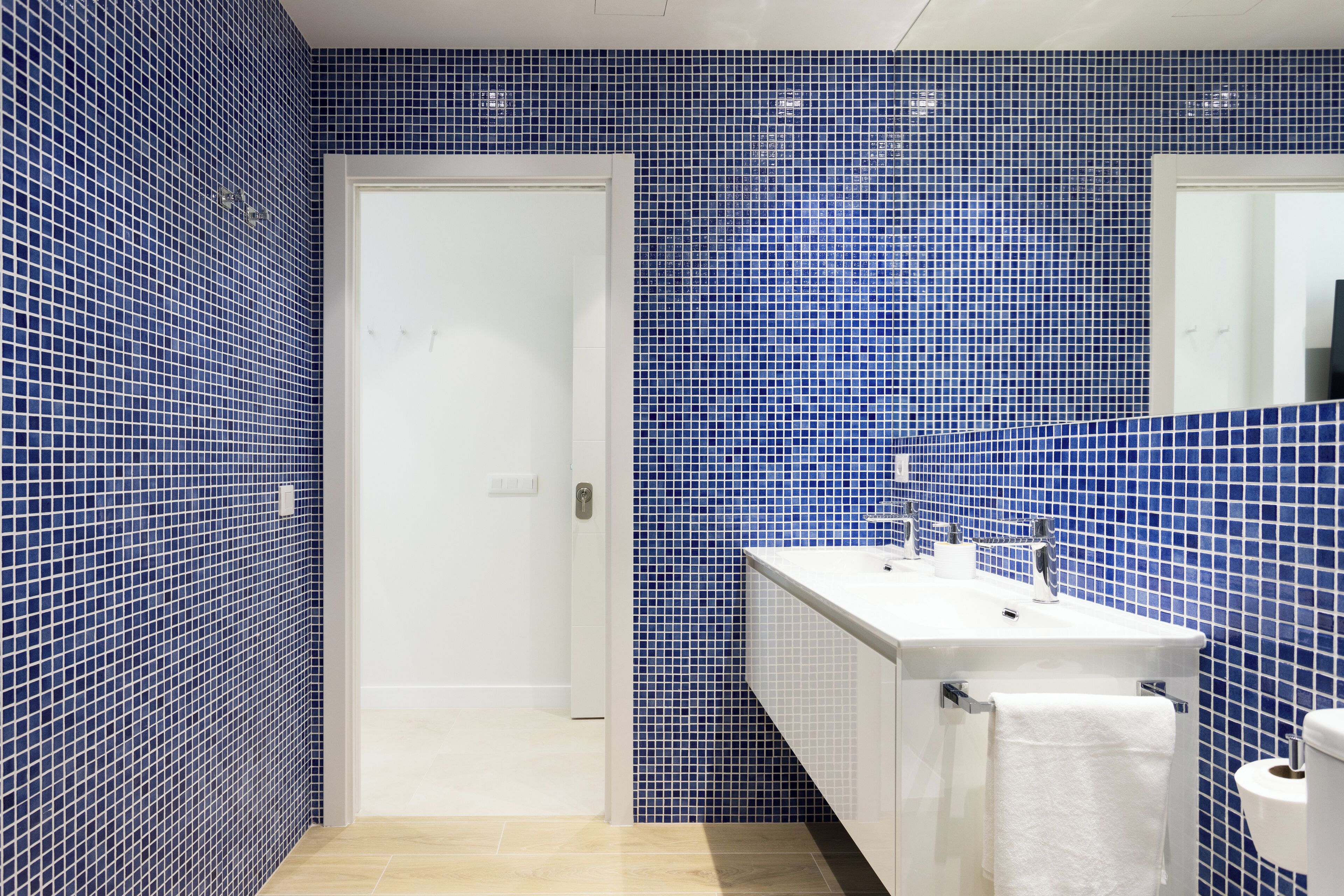Une salle de bain avec des carreaux de mosaïque bleus, un lavabo blanc et des toilettes blanches.