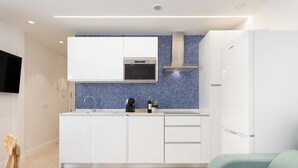 Una cucina moderna con mobili bianchi, uno schienale piastrellato blu e un forno integrato.