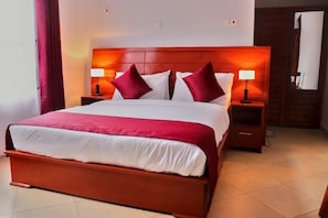 A hotel room with a large bed, two bedside tables, and a wooden headboard. - VIGO LODGE (Arusha)