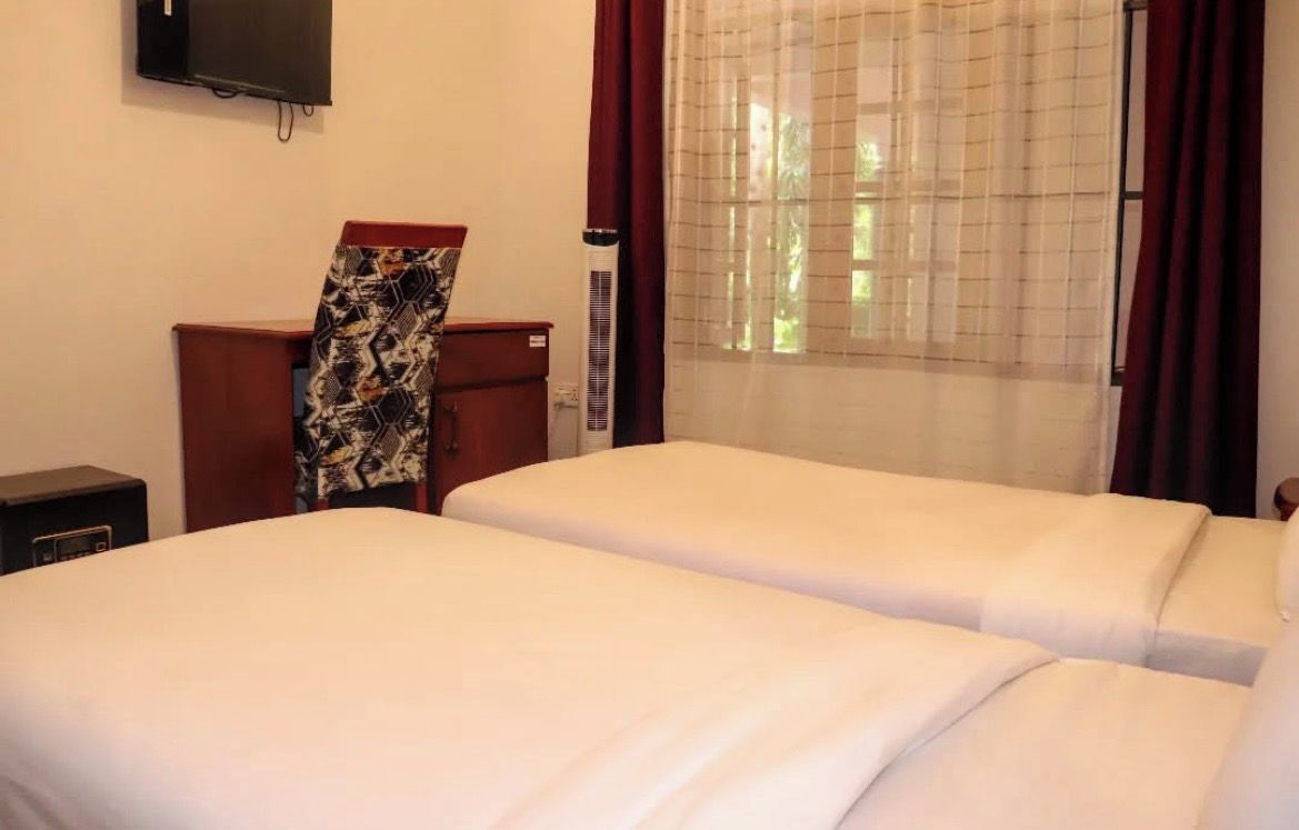 Une chambre d’hôtel avec deux lits, un bureau, une télévision et une fenêtre avec des rideaux.
