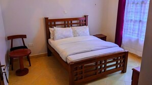 Ein Schlafzimmer mit einem hölzernen Bett, einem kleinen runden Tisch und einem Stuhl.