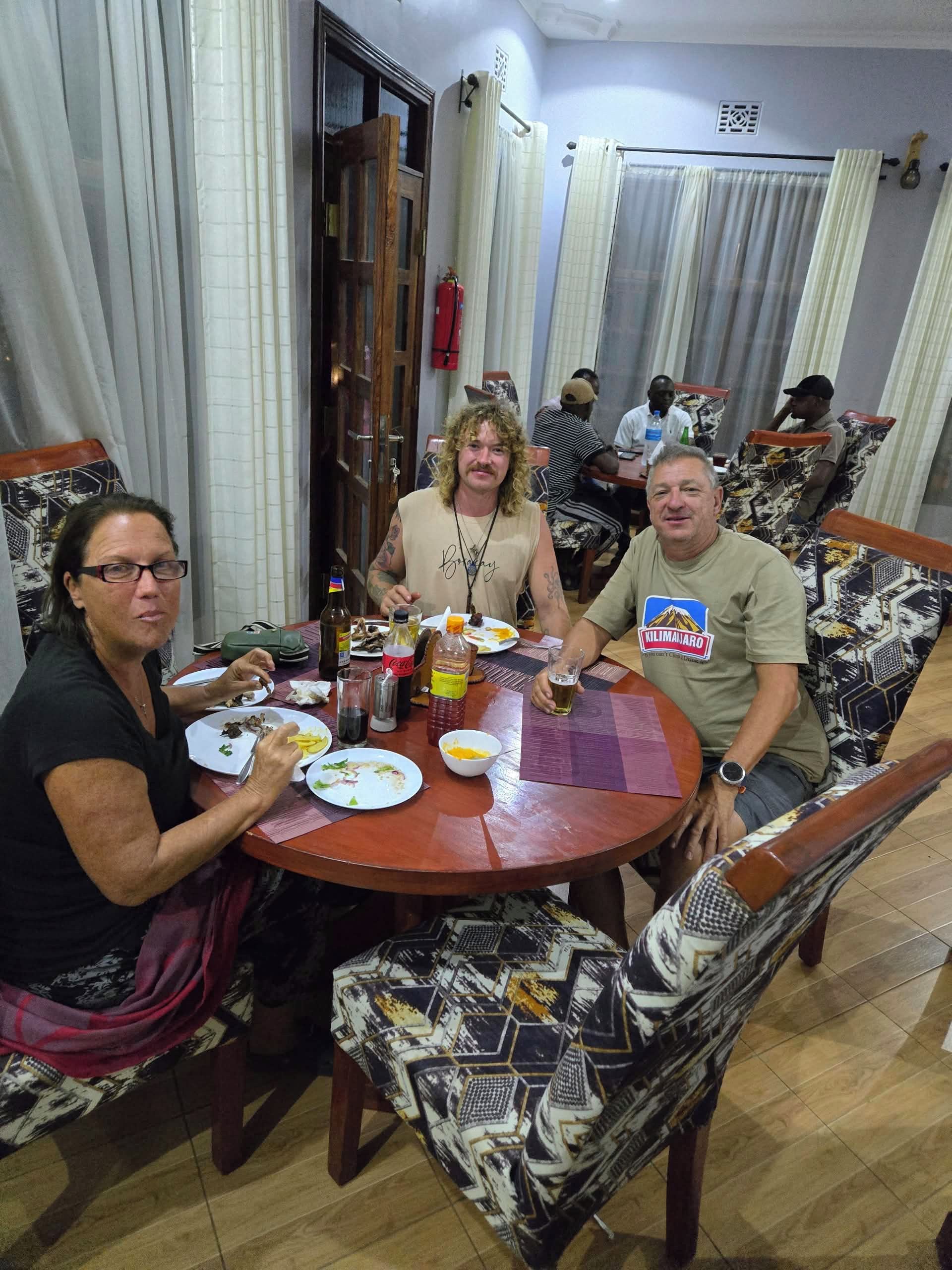 A dining area with a round table, chairs with patterned upholstery, and a variety of tableware and condiments.