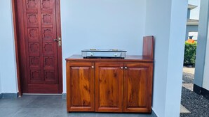 A wooden cabinet with a stove on top, a red door, and a white wall. - Small White House Njiro (Arusha)