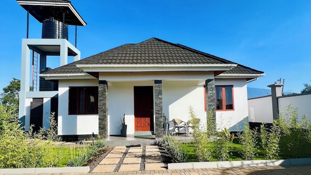 A modern house with a tiled roof, a central entrance, and a water tank on the left. - Small White House Njiro (Arusha)