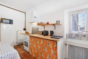 Une cuisine compacte équipée d’un four à micro-ondes, d’un grille-pain, d’une bouilloire et d’une petite machine à café posée sur le plan de travail.