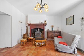 Un salon avec une cheminée, un canapé, une table et un lustre.