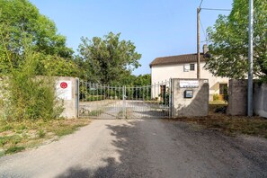 Une entrée fermée par un portail mène à un bâtiment sur lequel est apposée une enseigne indiquant « ÉLEVAGE D’HUÎTRES » et un numéro de téléphone.