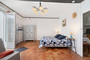 A bedroom with a bed, a desk, a wardrobe, and a hanging rack.