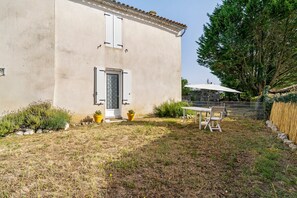Une maison avec une porte, une fenêtre et un petit patio comprenant une table et des chaises.