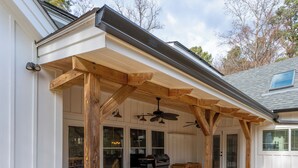 A covered patio area with wooden beams and a ceiling fan. - Spacious 4-bedroom farmhouse in beautiful Appling with AC (Appling)