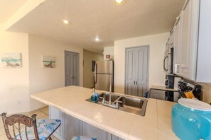 A kitchen with a central island, stainless steel appliances, and a blue water dispenser. - Sonoran Spa N 501 1 Bed 1 Bath (Puerto Peñasco)