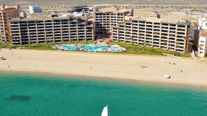 A coastal hotel with multiple buildings, a beach, and a sailboat in the water. - Sonoran Spa N 501 1 Bed 1 Bath (Puerto Peñasco)