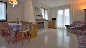 Un soggiorno con camino, zona pranzo con tavolo e sedie, un divano e una televisione.