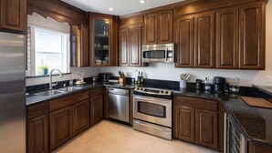 Una cucina moderna con mobili in legno scuro, elettrodomestici in acciaio inossidabile e un piano di lavoro nero.
