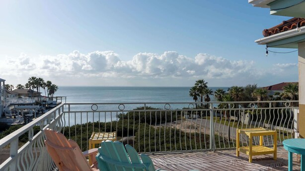 Un balcone con vista sull'oceano, arredi da esterno e una ringhiera.