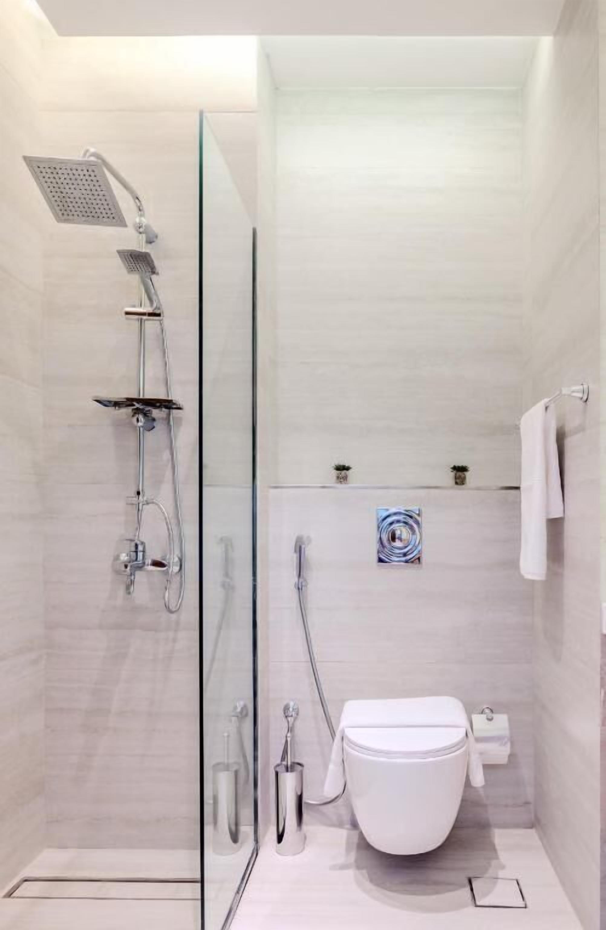 Une salle de bain moderne avec une douche à parois de verre, des toilettes et un petit porte-serviettes.