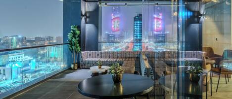 A modern lounge with a city view, a round table, and patterned seating.