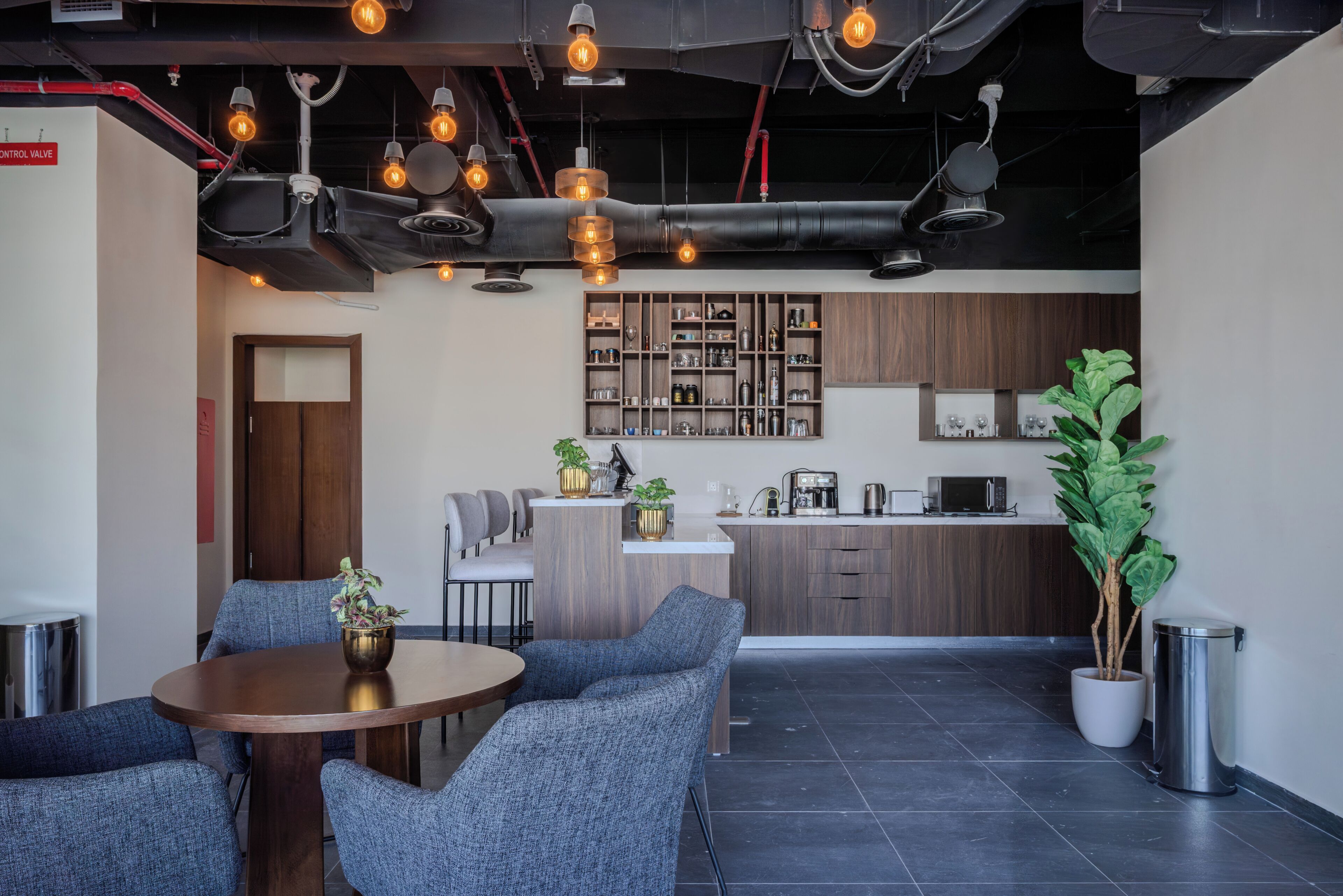 A modern kitchen with wooden cabinets, a central island, and a dining area with a round table and blue chairs.