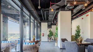 A modern interior with round tables, chairs, and large windows offering views.