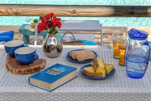 A table with a book, two cups, a vase with flowers, a pitcher, and slices of cake. - Villa Angiolina - Ideal for 5 people with A/C and Wi-Fi (Sardegna)