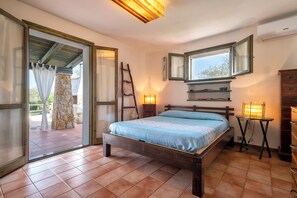 A bedroom with a bed, a wooden ladder, a window with a view, and a small table with a lamp. - Villa Angiolina - Ideal for 5 people with A/C and Wi-Fi (Sardegna)