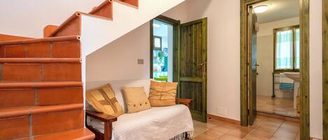 A staircase leading to a bedroom with a bed, a wooden door, and a bathroom visible through an open door.