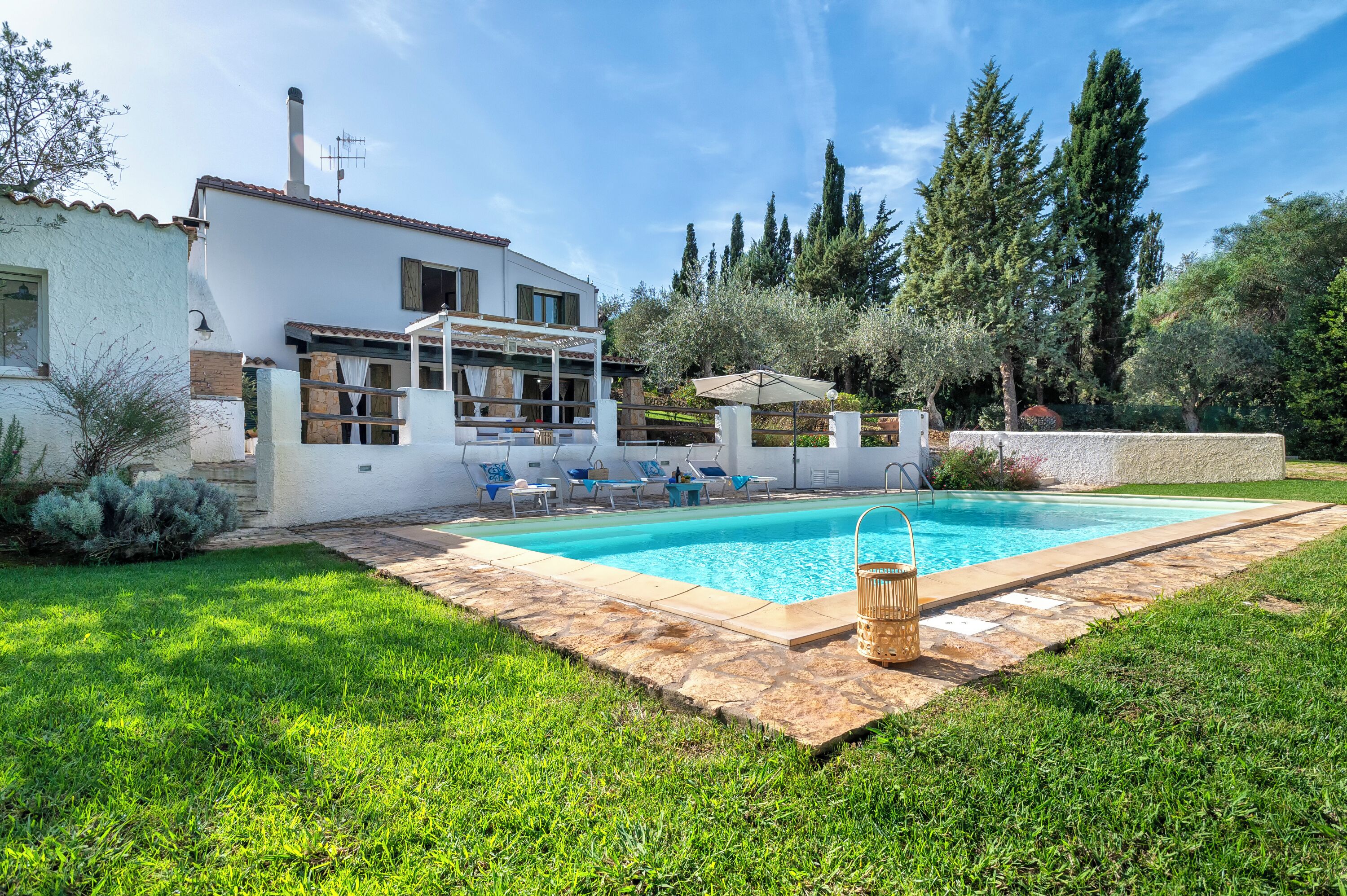 Ein modernes Haus mit Swimmingpool, Sitzgelegenheiten im Freien und einem gepflegten Garten.
