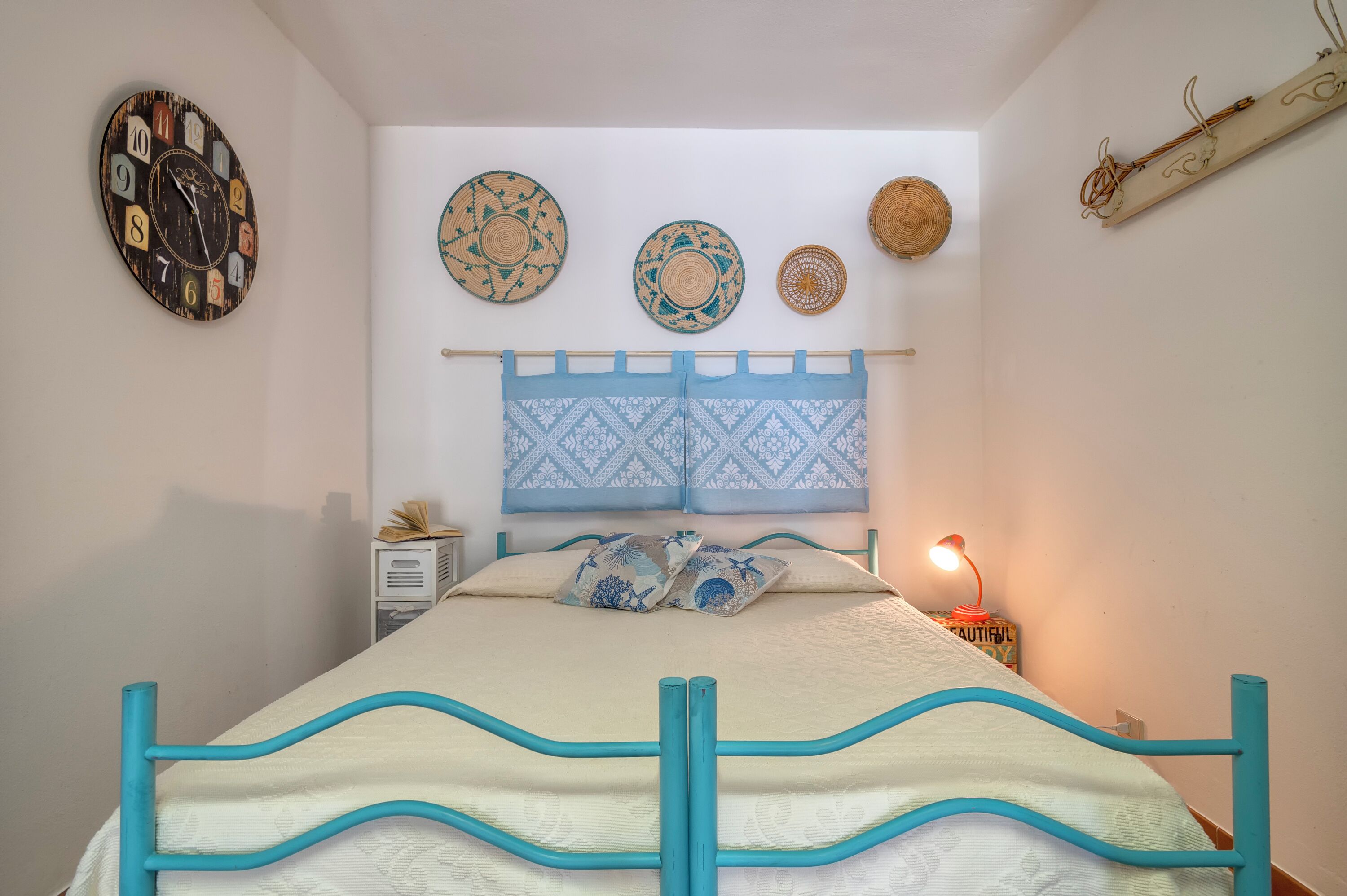 Une chambre à coucher avec un lit, une horloge murale et des assiettes décoratives.
