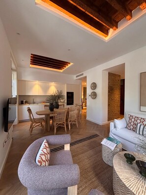 A modern living room with a sofa, a dining area with chairs and a table, and a kitchen in the background. - Elegant 3BD Apartment in Malaga Plaza Marina II (Málaga)