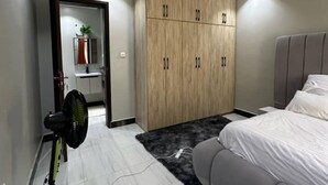 Een moderne slaapkamer met een bed, een garderobe, een spiegel en een ventilator.