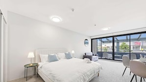 A modern hotel room with a large bed, bedside tables, a desk, and a view of the street. - MetaWiseBnB Cronulla Beach Walk to Train & Shops 4 (Cronulla)