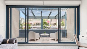 A balcony with a glass door, two chairs, a small table, and a sofa. - MetaWiseBnB Cronulla Beach Walk to Train & Shops 4 (Cronulla)