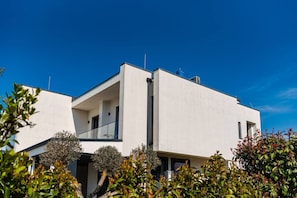 Um edifício moderno de dois andares com telhado plano, janelas amplas e uma varanda.