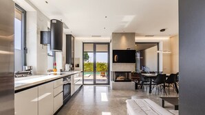 A modern kitchen with a large island, built-in appliances, and a dining area with a table and chairs.