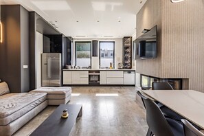 A modern kitchen with a built-in oven, a dining area with a table and chairs, and a seating area with a sofa and a coffee table.