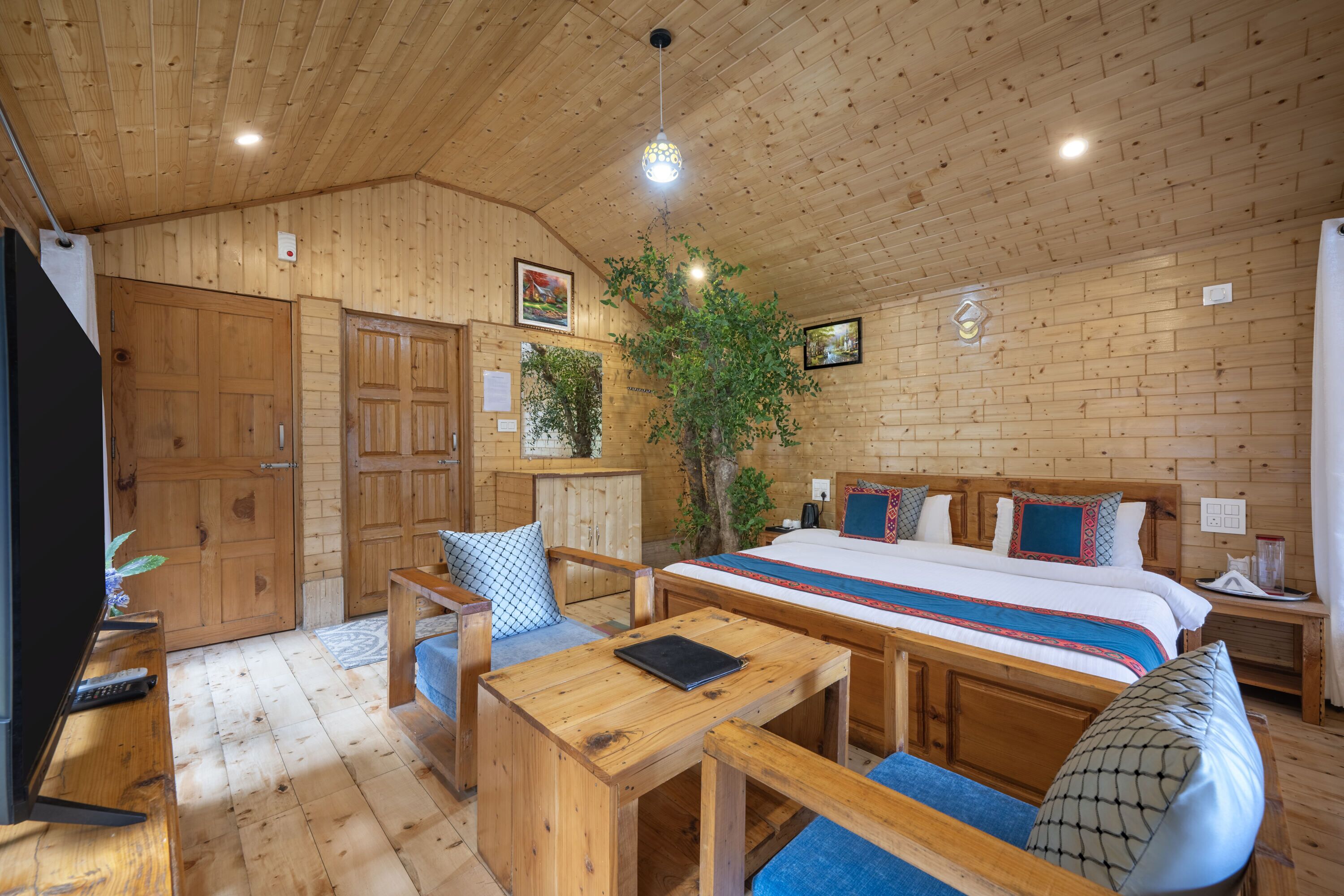 Una habitación con paneles de madera, una cama, un escritorio, una silla y un televisor.