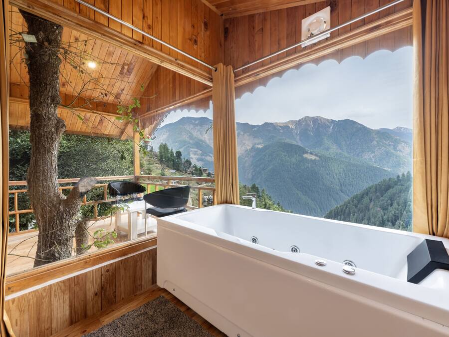 Una cabaña de madera con una bañera grande y vistas a las montañas.