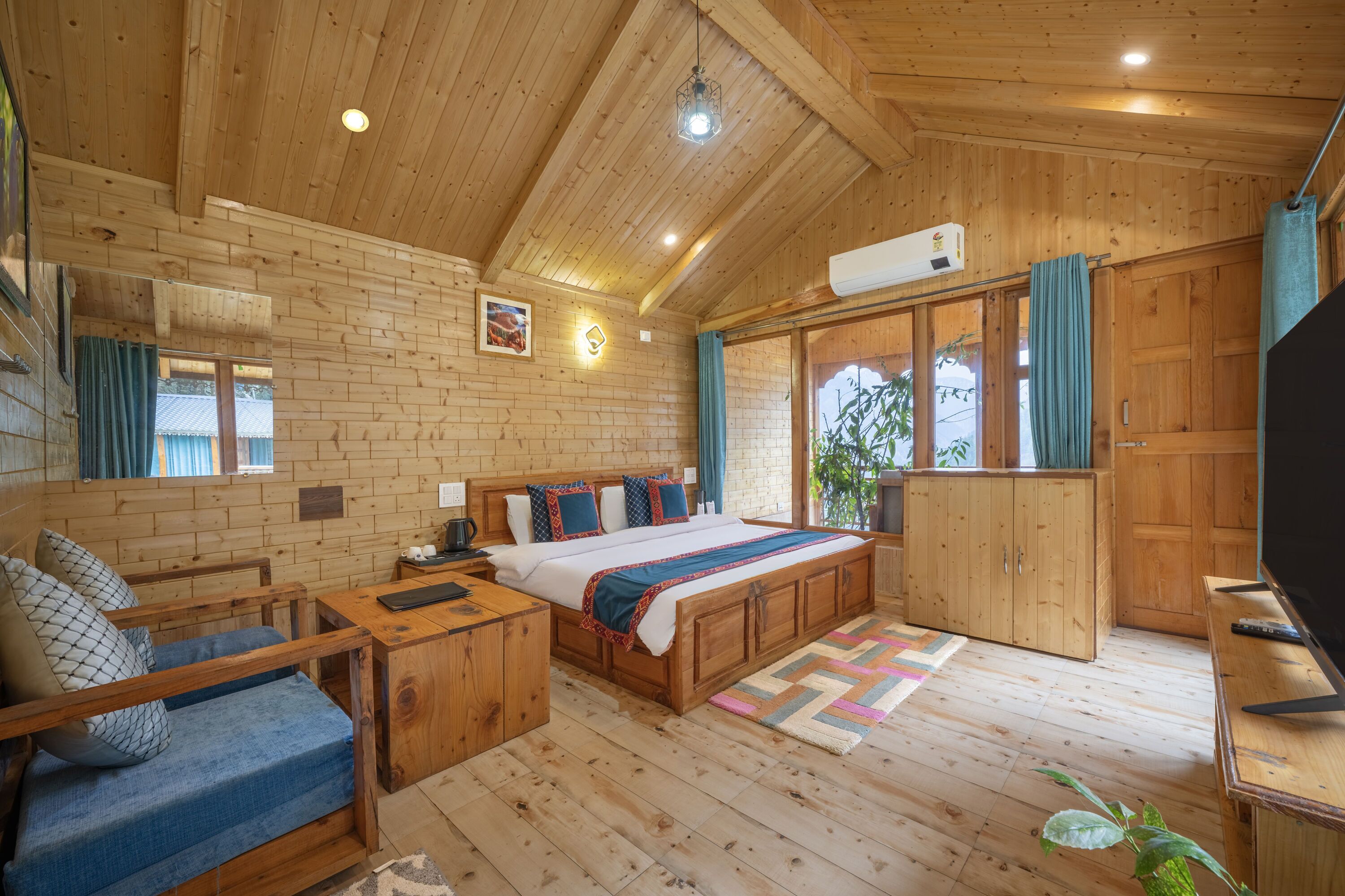 L’intérieur d’un chalet en bois, avec un lit, un canapé, une télévision et des murs en bois.