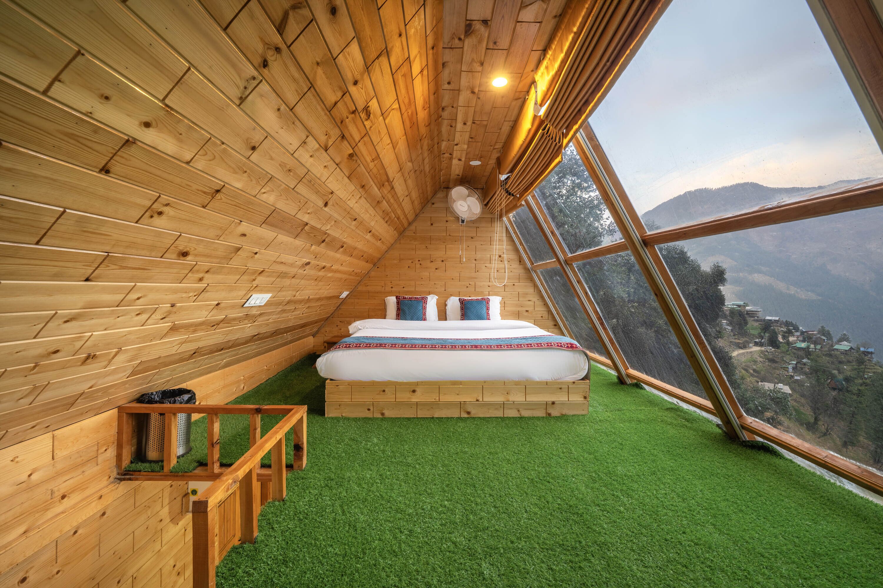 Una habitación de madera con una cama, una ventana y vistas al paisaje.