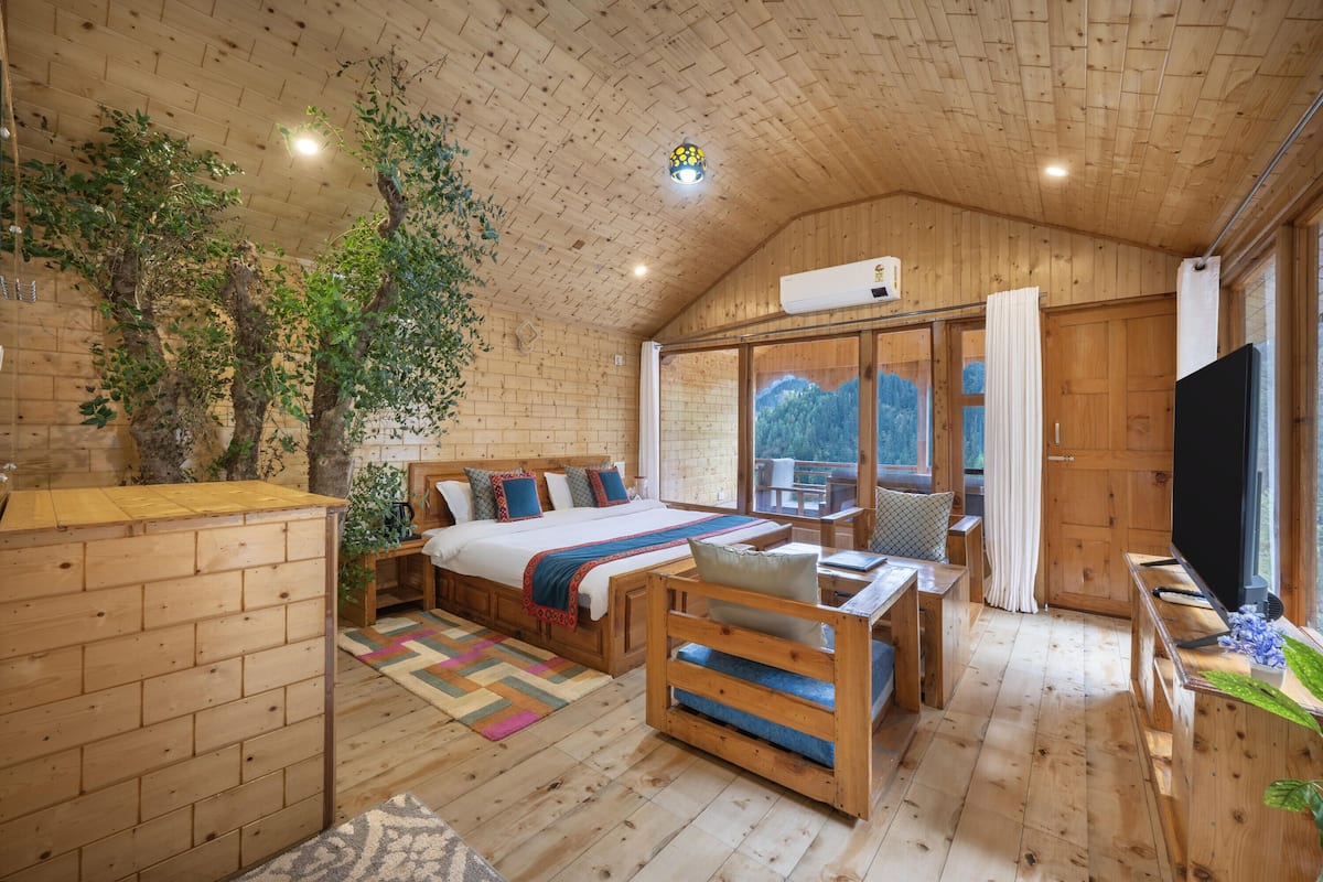 A wooden cabin interior with a bed, seating area, and a TV.