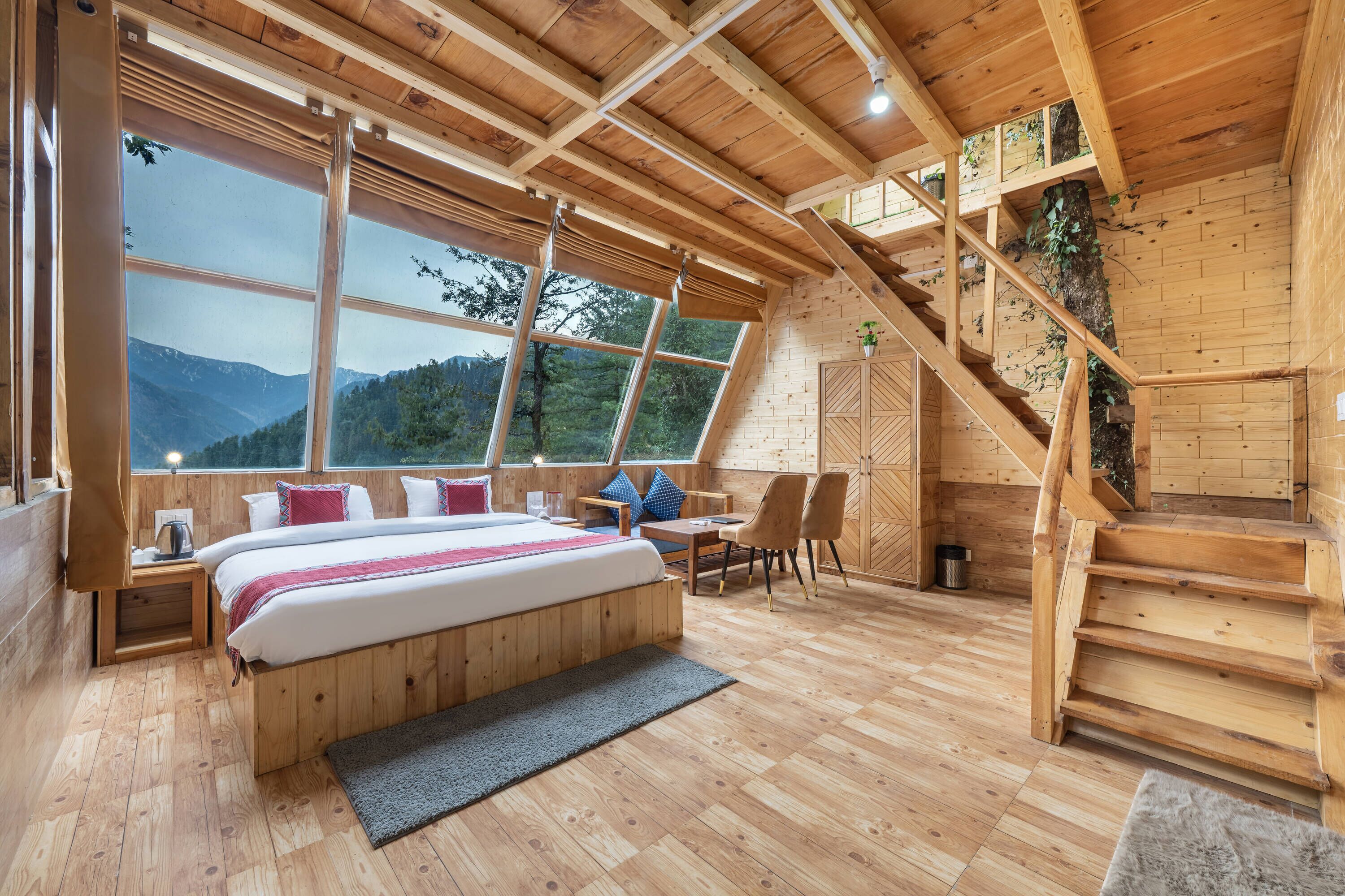 Un dormitorio de cabaña de madera con una cama grande, un escritorio y una escalera.